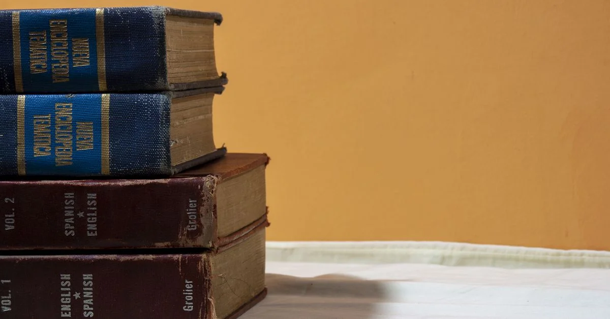 Un gros plan de dictionnaires anglais-espagnol vintage empilés sur une table contre un fond chaleureux.