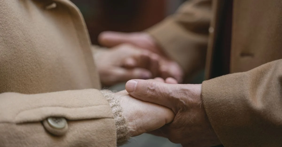 Moment intime de deux personnes se tenant la main dans des manteaux chauds, illustrant connexion et chaleur.