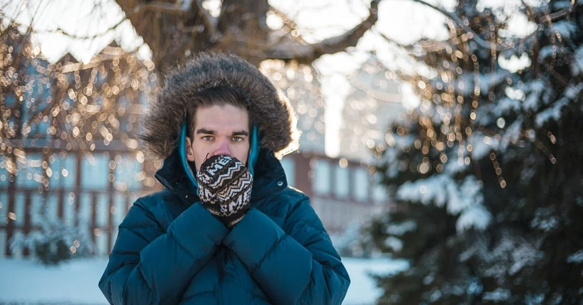 Un homme se réchauffant dans un manteau d'hiver à l'extérieur dans la neige à Dnipro, Ukraine.