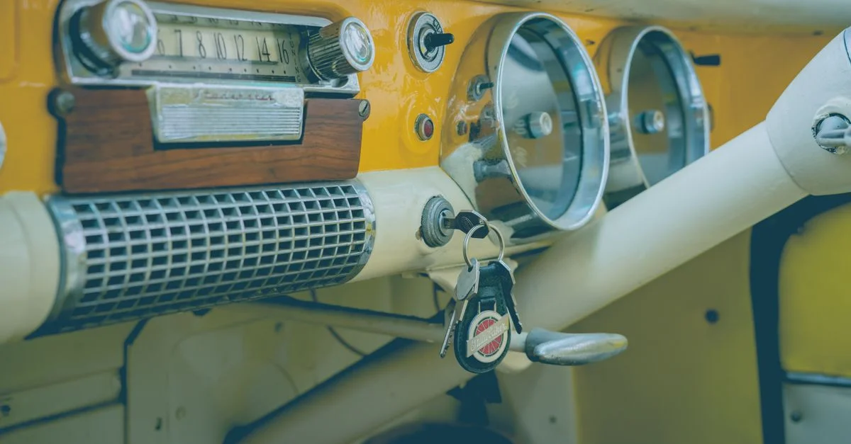 Gros plan sur le tableau de bord d'une voiture vintage classique avec une radio analogique, un compteur de vitesse et des clés.