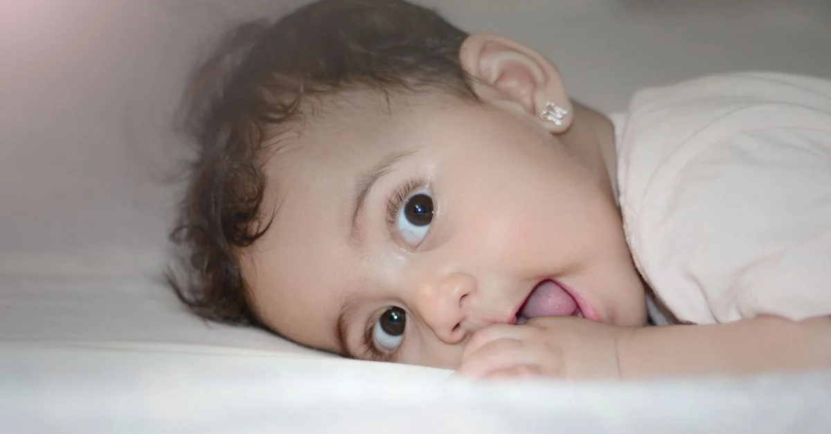 Charmante petite fille aux grands yeux marron allongée sur le lit, montrant innocence et mignonnerie.