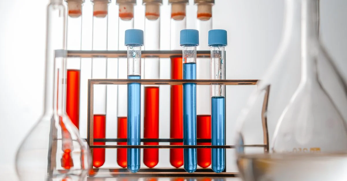 Gros plan sur des éprouvettes contenant des liquides bleus et rouges dans un environnement de laboratoire.